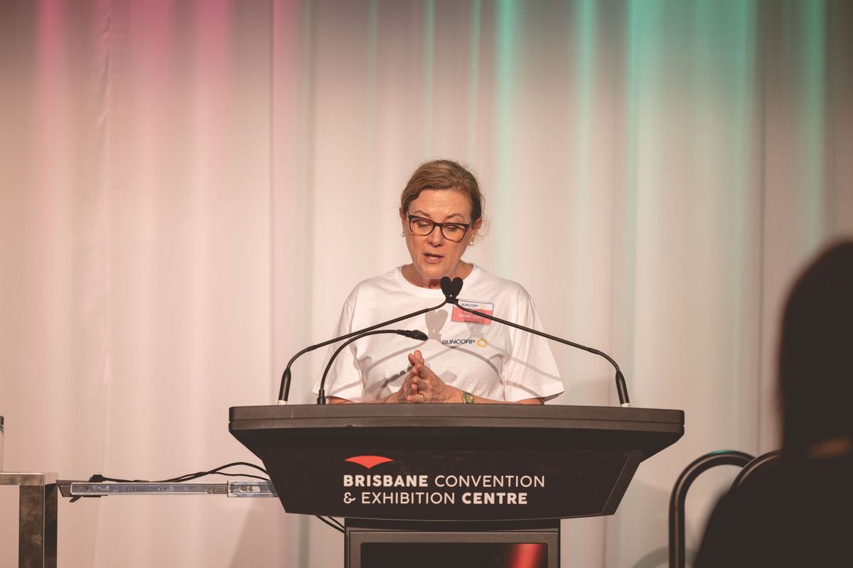 A speaker addressing the room from a lectern at the Brisbane Convention and Exhibition Centre